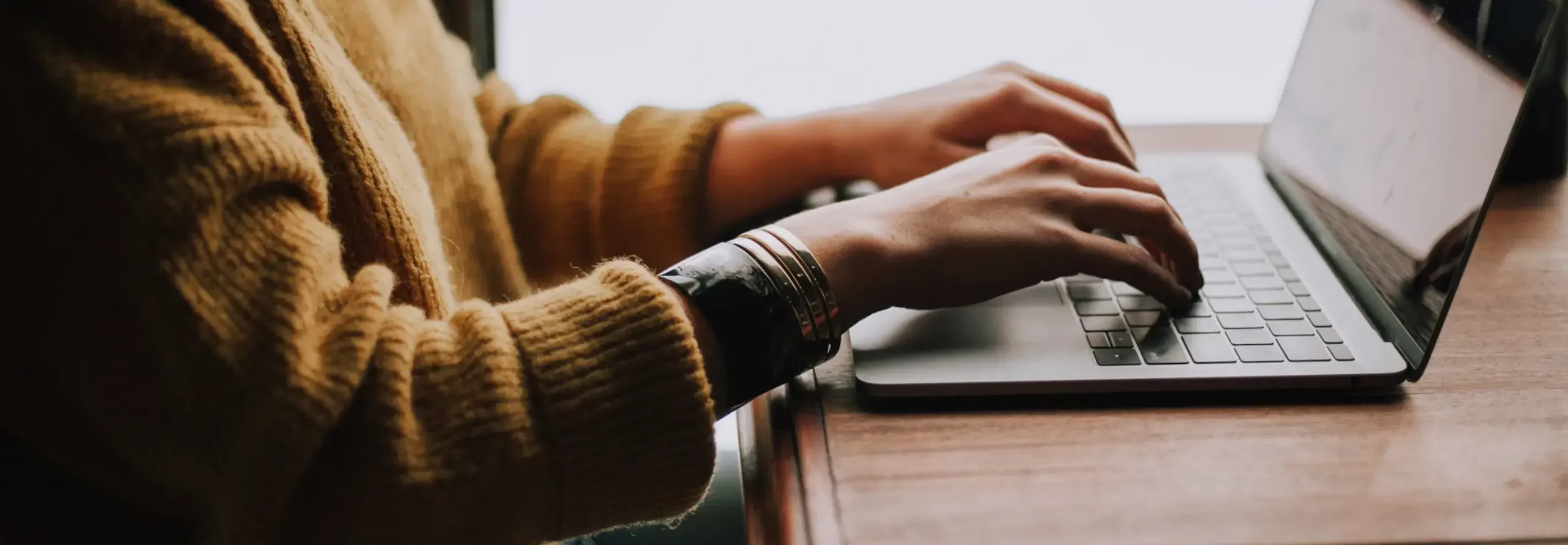 Person sitting at a table writing on a laptop