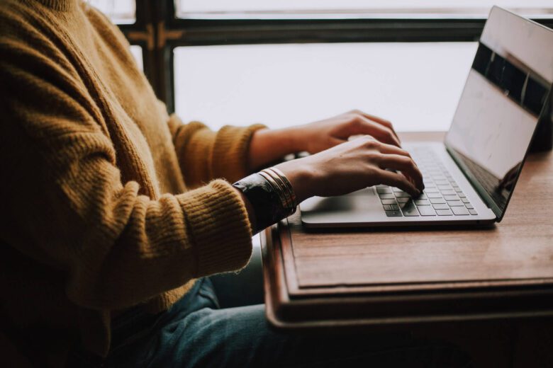 Person sitting at a table writing on a laptop