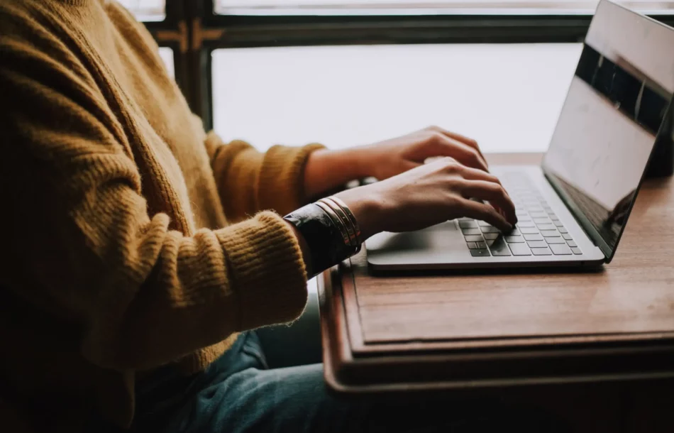 Person sitting at a table writing on a laptop